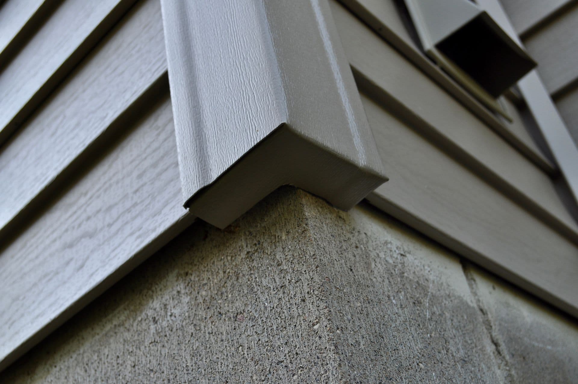 Close-up corner detail of gray siding installation